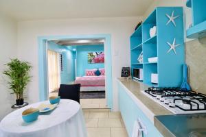 a kitchen with blue cabinets and a table in a room at ShineAwayHomes -AC Beachfront RAROTONGA in Matavera