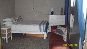 a small bedroom with a bed and a dresser at Waterkant 4B in Jeffreys Bay