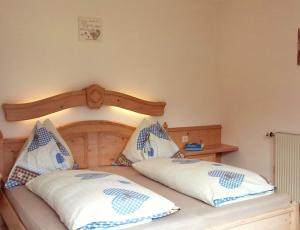 Bett mit einem Kopfteil aus Holz und 2 Kissen in der Unterkunft Landhaus Hirterhütte in Abtenau