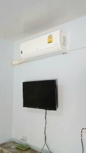 a television hanging from a wall with a shelf at Nong Or Blue House Resort in Sukhothai