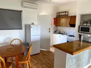 cocina con mesa y nevera blanca en Waldeck Heights, en Geraldton