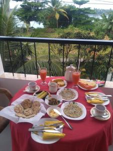 ベントータにあるMovi Holiday Apartmentの赤いテーブル布の上に朝食用の食べ物をかけたテーブル