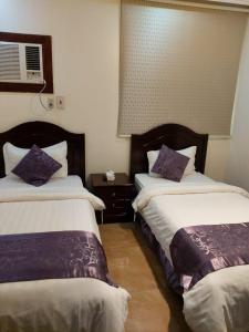 a hotel room with two beds with purple pillows at Beyoot Alsharq Furnished Units in Al Khobar