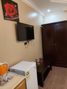 阿可賀巴的住宿－Beyoot Alsharq Furnished Units，带冰箱的厨房和墙上的电视