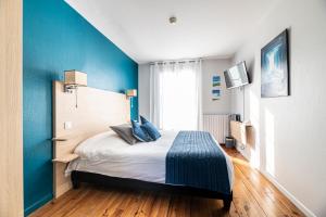 a bedroom with a bed with a blue wall at Hotel Helios - Golf in Salies-de-Béarn