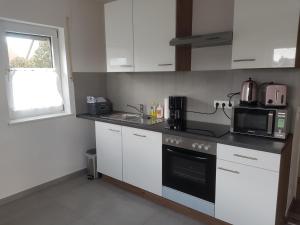 a kitchen with white cabinets and a sink and a microwave at Ferienwohnung Eyb in Ansbach