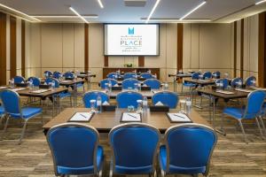 a conference room with tables and chairs and a screen at Millennium Place Barsha Heights Hotel in Dubai