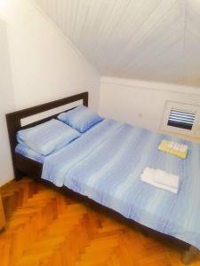 a bedroom with a bed with blue sheets and a window at Apartmani Braca2 in Kotor