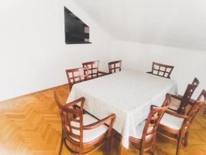 a dining room with a white table and wooden chairs at Apartmani Braca2 in Kotor