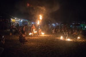 un grupo de personas sentadas en una playa con fuegos en D Rock Garden Resort en Perhentian Island