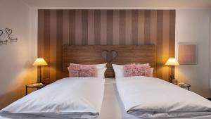a bedroom with two beds with white sheets and pink pillows at Bayern Resort Hotel - Adults only - mit Zugspitzblick - Eibsee-Nähe - Wellnessbereich - Naturpool im Sommer in Grainau