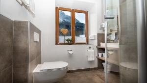 a bathroom with a toilet and a window at Bayern Resort Hotel - Adults only - mit Zugspitzblick - Eibsee-Nähe - Wellnessbereich - Naturpool im Sommer in Grainau