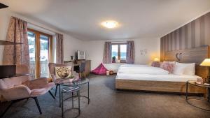 a hotel room with a bed and a chair at Bayern Resort Hotel - Adults only - mit Zugspitzblick - Eibsee-Nähe - Wellnessbereich - Naturpool im Sommer in Grainau