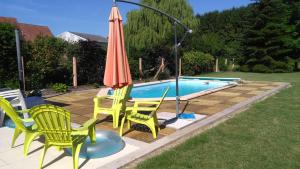 un patio con sillas y una sombrilla junto a la piscina en Gîte HEINTZ en Schleithal