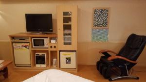 sala de estar con silla y TV en Hotel GOLF Yokohama (Adult Only) en Yokohama