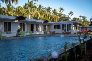 a villa with a swimming pool in front of a house at Golden Sands Resort, Morjim in Morjim