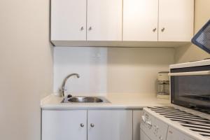 eine weiße Küche mit einer Spüle und einer Mikrowelle in der Unterkunft Irodotou Studio in Thessaloniki + 9 Fotos