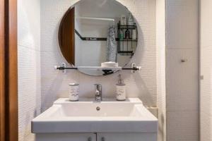 bagno con lavandino bianco e specchio di Irodotou Studio a Salonicco