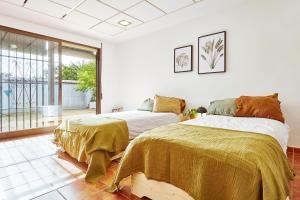 2 letti in una camera da letto con finestra di Casa LLimona: La casa perfecta para tus vacaciones. a San Vicente del Raspeig