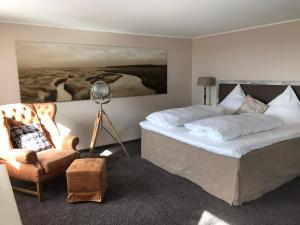 a bedroom with a bed and a chair and a painting at Hotel Strand No.1 in Sankt Peter-Ording