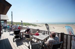 un grupo de personas sentadas en mesas en la playa en toplocatie Middelkerke frontal sea view, en Middelkerke