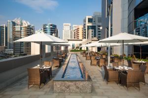 Millennium Place Barsha Heights Hotel Apartments في دبي: مطعم بطاولات ومظلات على السطح