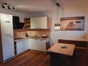 cocina con armarios blancos y mesa de madera en Apart Alexandra, en Strass im Zillertal