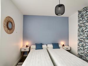 - une chambre avec 2 lits dotés d'oreillers bleus et d'un miroir dans l'établissement Grain de Sable, à Royan
