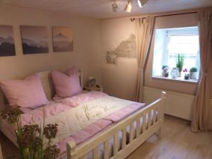 Schlafzimmer mit einem Bett mit rosa Kissen und einem Fenster in der Unterkunft EifelverWeiler in Weiler