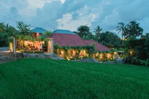 a house with a green lawn in front of it at Pangkung Sari Bed and Breakfast in Canggu