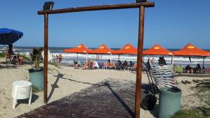an orange canopy on a beach with people sitting in chairs at Rota do Sol Praia Hotel in Guaratuba