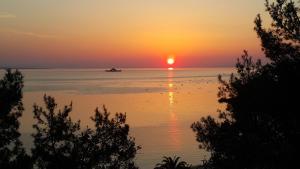 a sunset over the water with a boat in the distance at Villa Victoria by La Scala Beach in Limenas