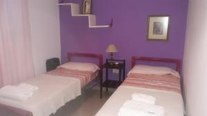 2 camas en una habitación con paredes moradas en San Luis Centro en San Luis