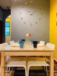 a table with chairs and a clock on the wall at Ammar Homestay in Kuala Terengganu