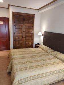 sypialnia z dużym łóżkiem i drewnianymi drzwiami w obiekcie Hotel Chef Rivera w mieście Padrón