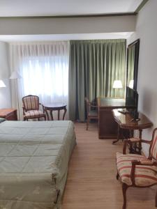 a hotel room with a bed and a table and a desk at Hotel Chef Rivera in Padrón
