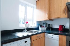 a kitchen with wooden cabinets and a sink at The Dakota - next to East Midlands Airport in Castle Donington