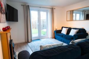 a living room with a blue couch and a window at The Dakota - next to East Midlands Airport in Castle Donington