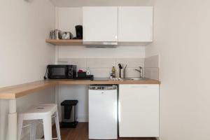 eine kleine Küche mit weißen Schränken und einem Geschirrspüler in der Unterkunft Studio Vahiny1 All comfort WIFI NETFLIX Parking in Saint-Nazaire