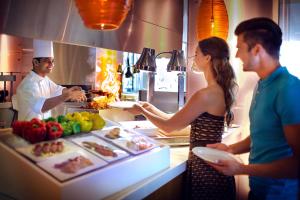 a man and a woman standing in a kitchen preparing food at Yas Island Rotana Abu Dhabi in Abu Dhabi
