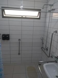 a white tiled bathroom with a sink and a window at Rota do Sol Praia Hotel in Guaratuba