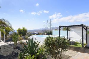 une villa avec une piscine et des palmiers dans l'établissement Casa Amanecer, à Tías