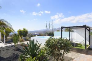 a villa with a swimming pool and palm trees at Casa Amanecer in Tías