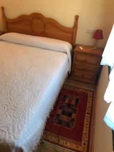 een slaapkamer met een bed en een dressoir met een lamp bij El Pajar in San Ciprián