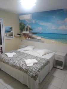 a bedroom with a bed with a painting of the beach at Hotel Rota do Sol in Guaratuba