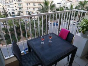 - une table avec deux verres de vin sur le balcon dans l'établissement Seabreeze Apartment, à San Pawl il-Baħar