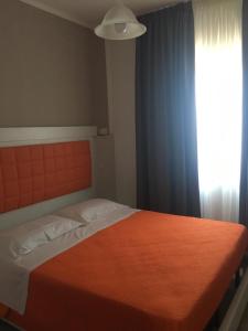 um quarto com uma cama com um cobertor laranja e uma janela em Piccolo Hotel Lamezia em SantʼEufemia Lamezia