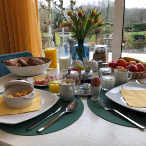 a table topped with plates of breakfast foods and juice at B&B Rosé in Valkenburg