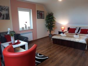 a living room with a bed and a red chair at Agroturystyka Gazdówka in Zakliczyn