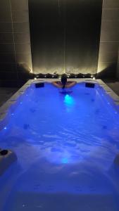 a large blue hot tub with a person in it at Le Castelet Sancy - Jardin & Spa in Le Mont-Dore